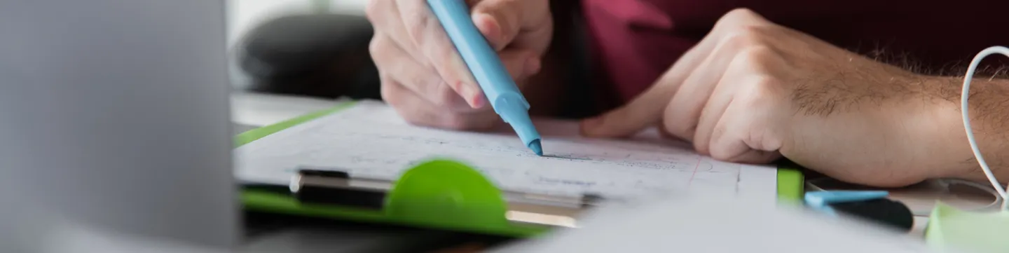 Persona tomando notas con un resaltador sobre una planilla de estudio
