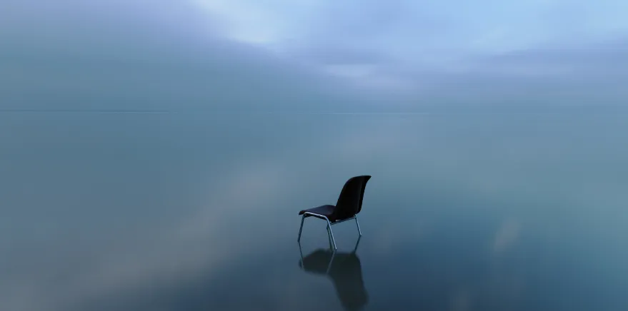 Una silla vacía sobre una superficie cubierta de agua, bajo un cielo gris
