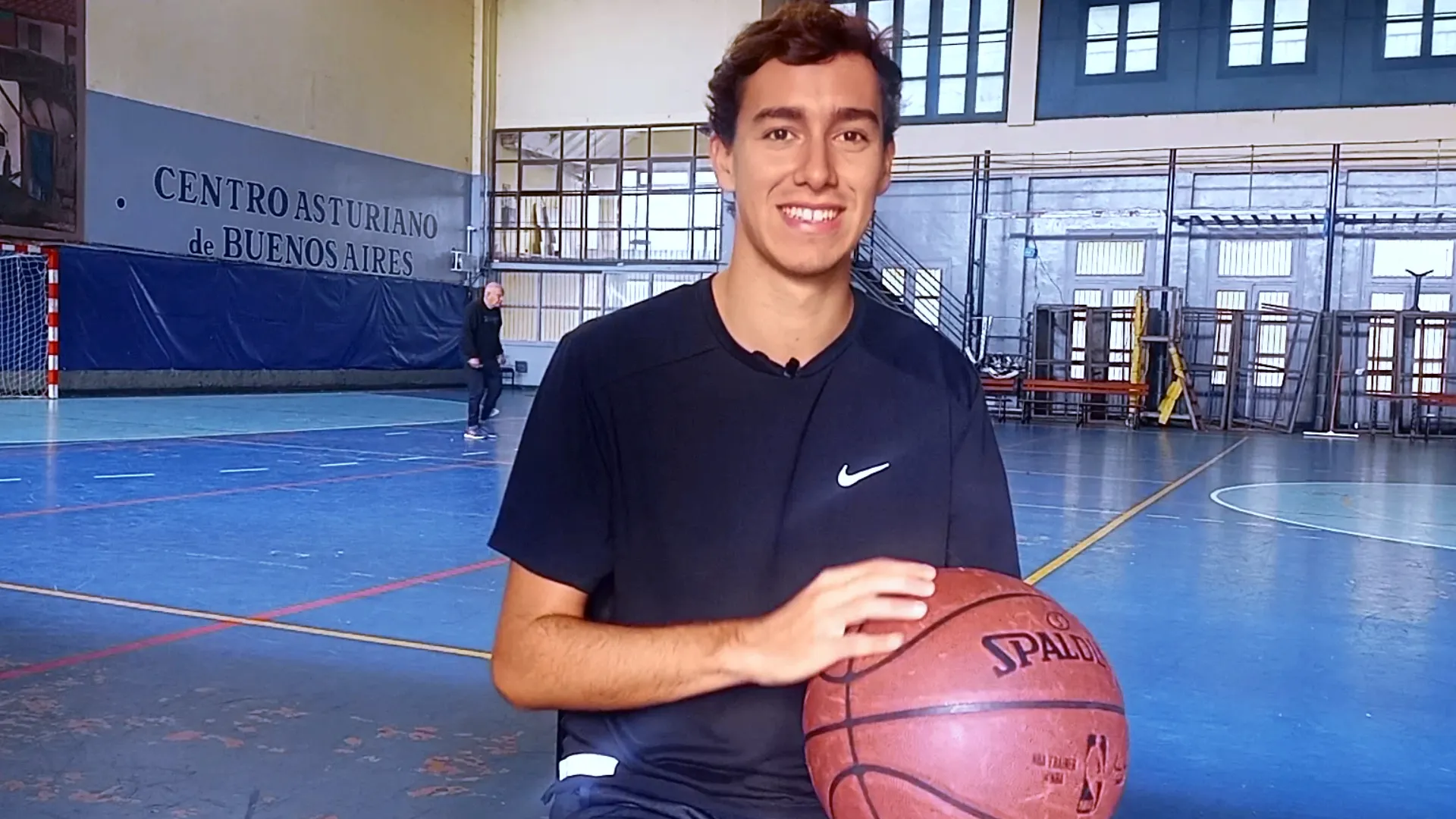 Lucas Fiorito sonriendo con una pelota de básquet en un gimnasio