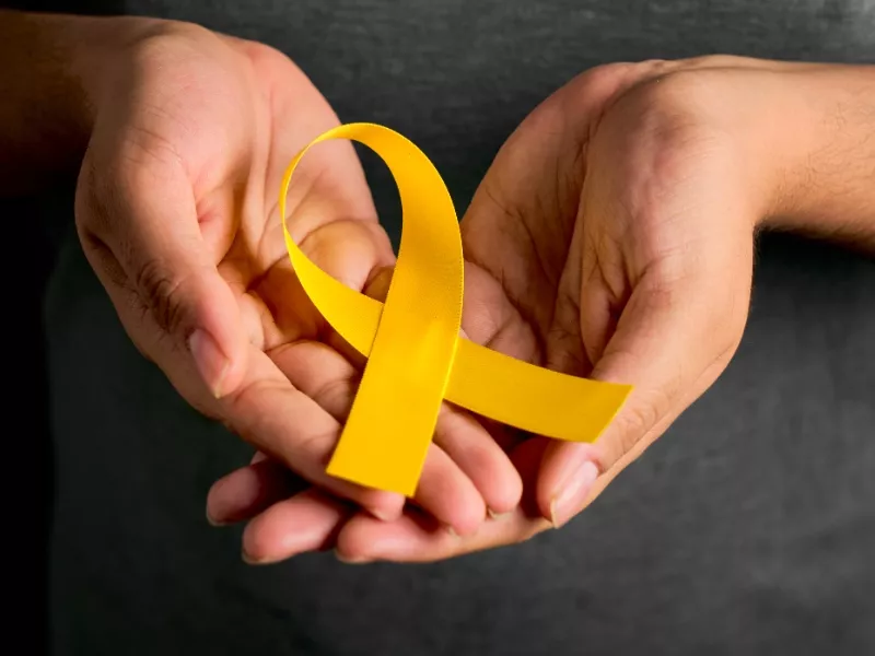 Manos sosteniendo un lazo amarillo, símbolo de la prevención del suicidio